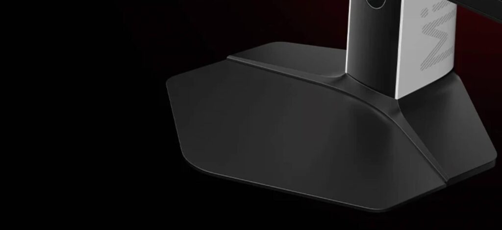 Close-up of a black, angular monitor stand with a vertical support against a dark background.
