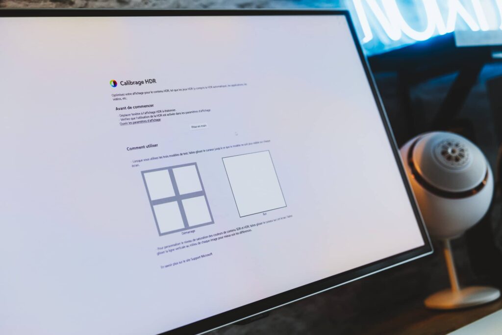 Monitor displaying HDR calibration instructions on a white screen, with a desktop microphone to the right.