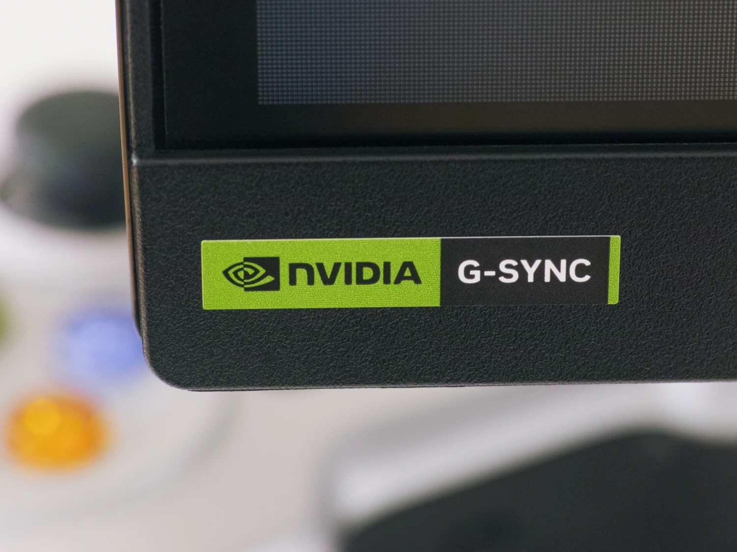 Close-up of an NVIDIA G-SYNC sticker on a monitor corner, showing the green NVIDIA logo and black G-SYNC panel.