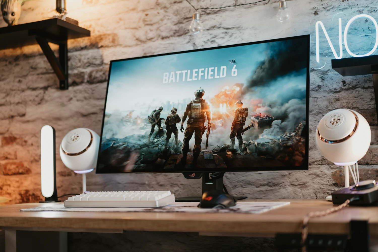 Battlefield 6 gameplay on a widescreen monitor with soldiers amid explosions in a ruined city.
